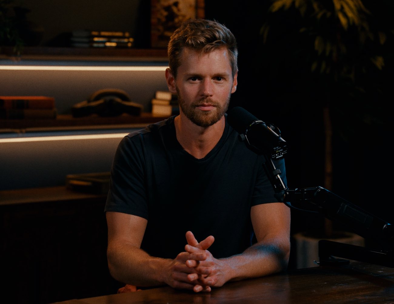 Josh Thifault seated at the Pressure Tested studio desk with his hands clasped, looking into the camera